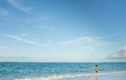 Hispanic boy running on beach