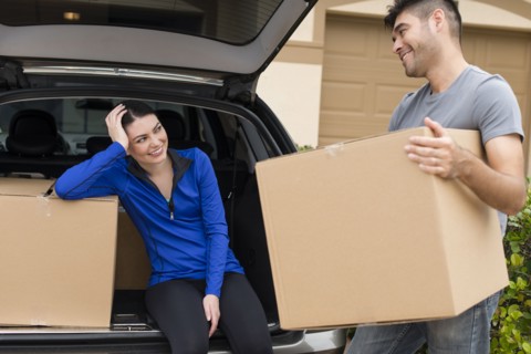 Hispanic couple carrying cardboard boxes near car