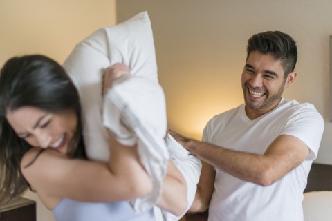 Hispanic couple having pillow fight