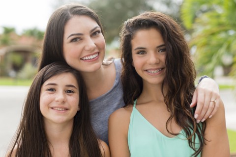 Mother and daughters smiling outdoors