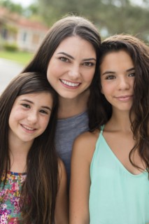 Mother and daughters smiling outdoors