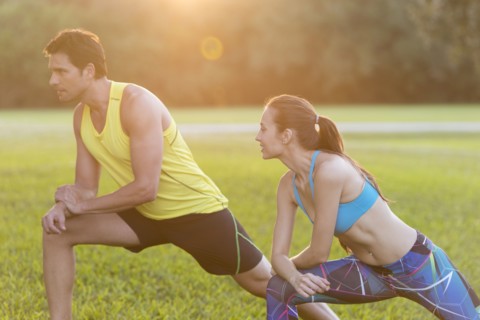 Couple stretching legs in field