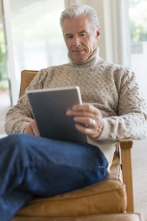 Caucasian man using digital tablet in armchair