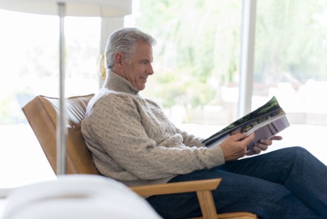 Caucasian man reading magazine in armchair
