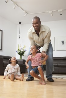 African American father playing with daughters in living room