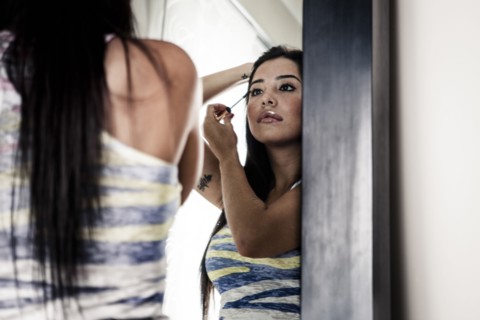 Woman applying makeup in mirror