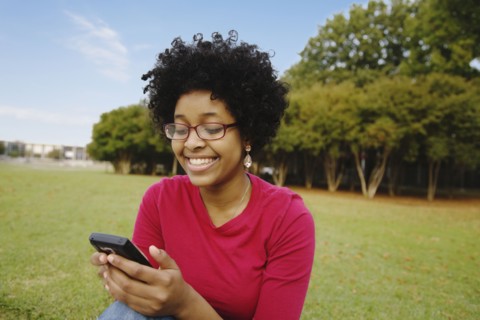 Mixed race woman text messaging on cell phone