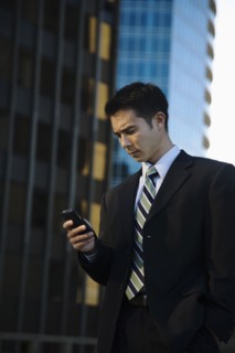Mixed race businessman text messaging on cell phone