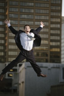 Excited mixed race businessman jumping in mid-air