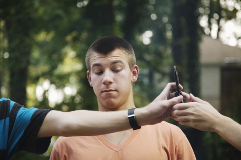 Teenager watching friends exchange cell phone