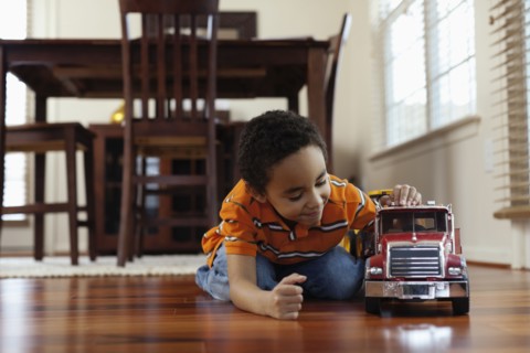 Mixed race boy playing with fire truck on floor