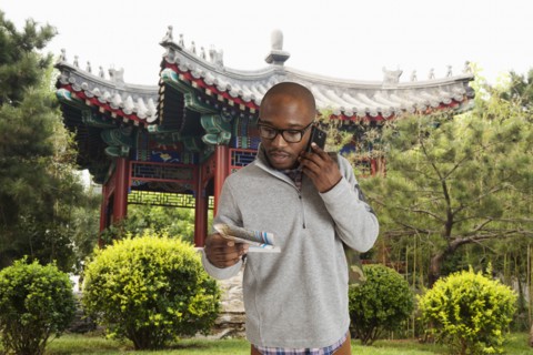 Black man reading map on city street