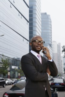 Black businessman talking on cell phone on city street