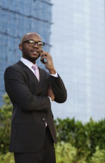 Black businessman talking on cell phone on city street