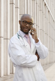 Black doctor talking on cell phone on city street