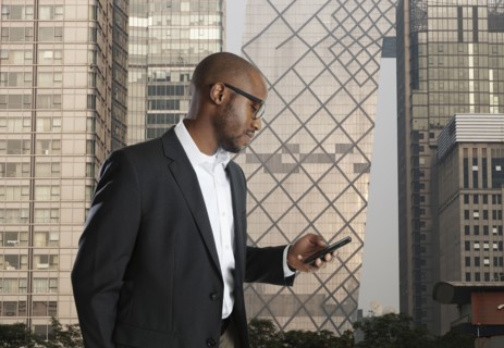 Black businessman using cell phone on city street