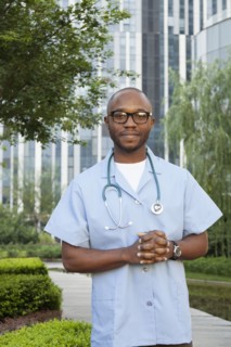 Black doctor smiling in urban park