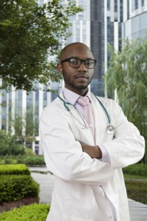 Black doctor standing in urban park