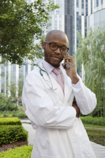 Black doctor talking on cell phone in urban park