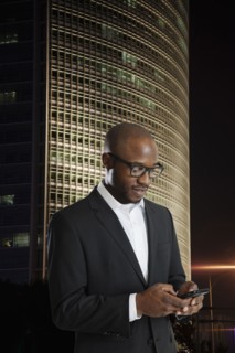 Black businessman using cell phone on city street