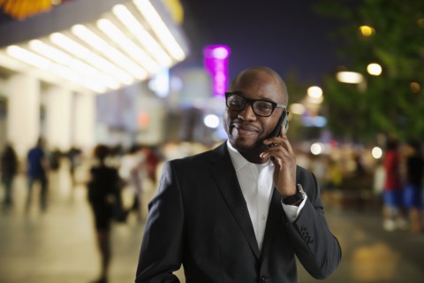 Black businessman talking on cell phone on city street