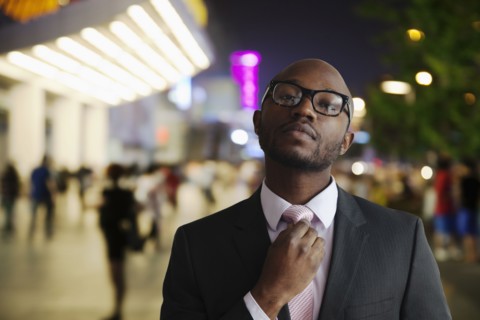 Black businessman adjusting tie on city street