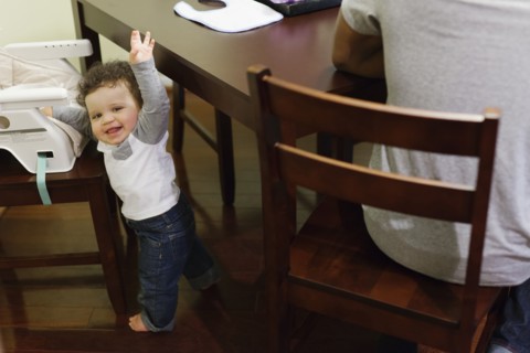 Baby climbing into high chair at table