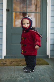 Caucasian boy wearing winter coat on porch