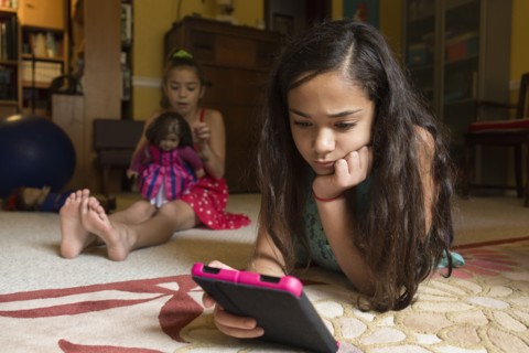 Mixed race girl using digital tablet on floor