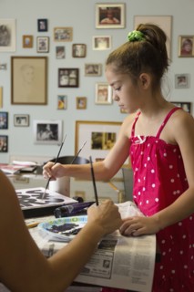 Mixed race mother and daughter painting sign