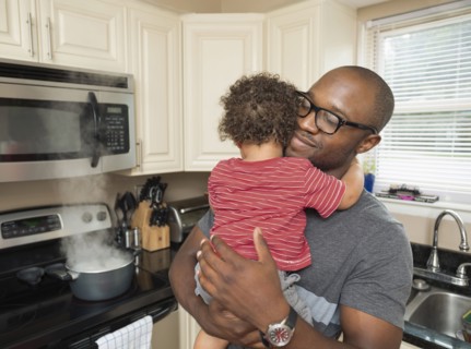Father holding toddler son in kitchen