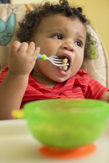 Mixed race toddler boy eating in high chair