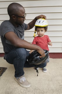 Father putting helmet on toddler son