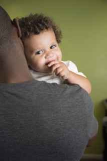 Father holding toddler son in bedroom