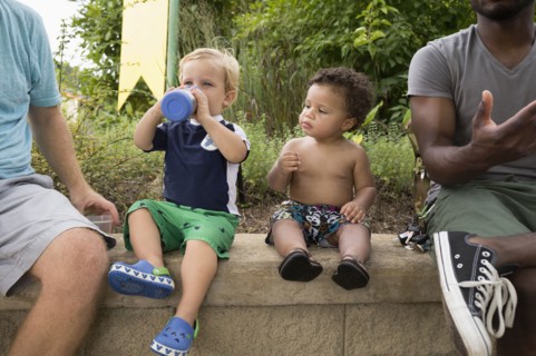 Fathers and toddler sons sitting together in park