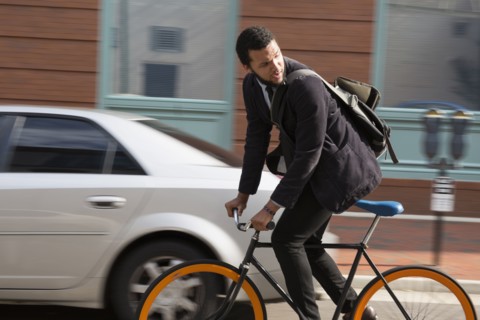 Mixed race businessman riding bicycle on city street