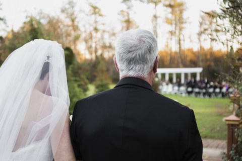 Caucasian father walking bride down aisle