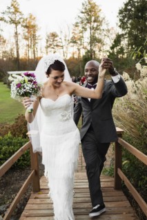 Newlywed couple walking on wooden footbridge