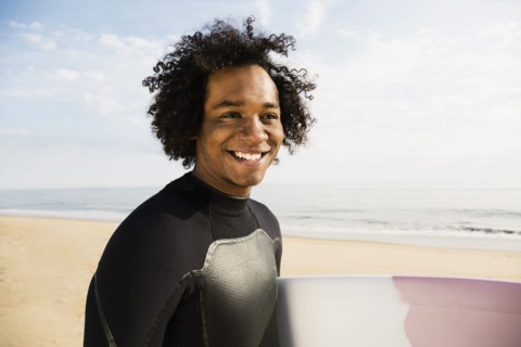 Mixed race surfer carrying board on beach