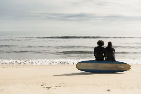 Surfers sitting on board on beach