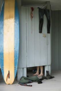 Caucasian surfer changing in beach hut