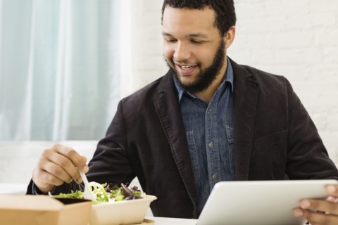 Mixed race businessman eating salad