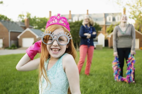 Caucasian girl playing dress up in park