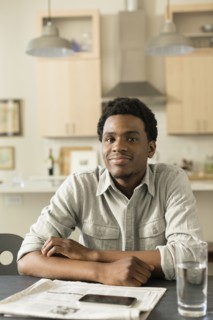 Black man reading newspaper at breakfast table