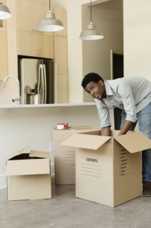 Black man unpacking cardboard box in new house