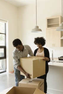Couple hauling cardboard boxes in new house