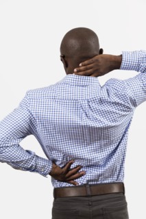 Black man rubbing aching back and neck