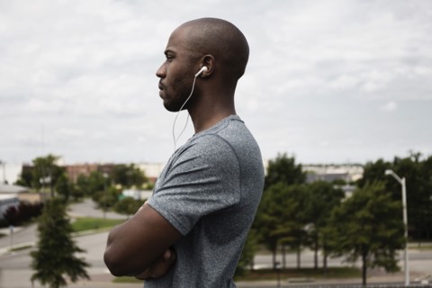 Black runner listening to earbuds in urban park