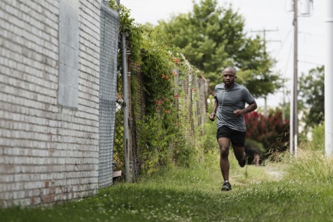 Black man running in urban grass