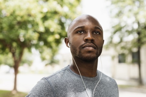 Black runner resting in park with earbuds
